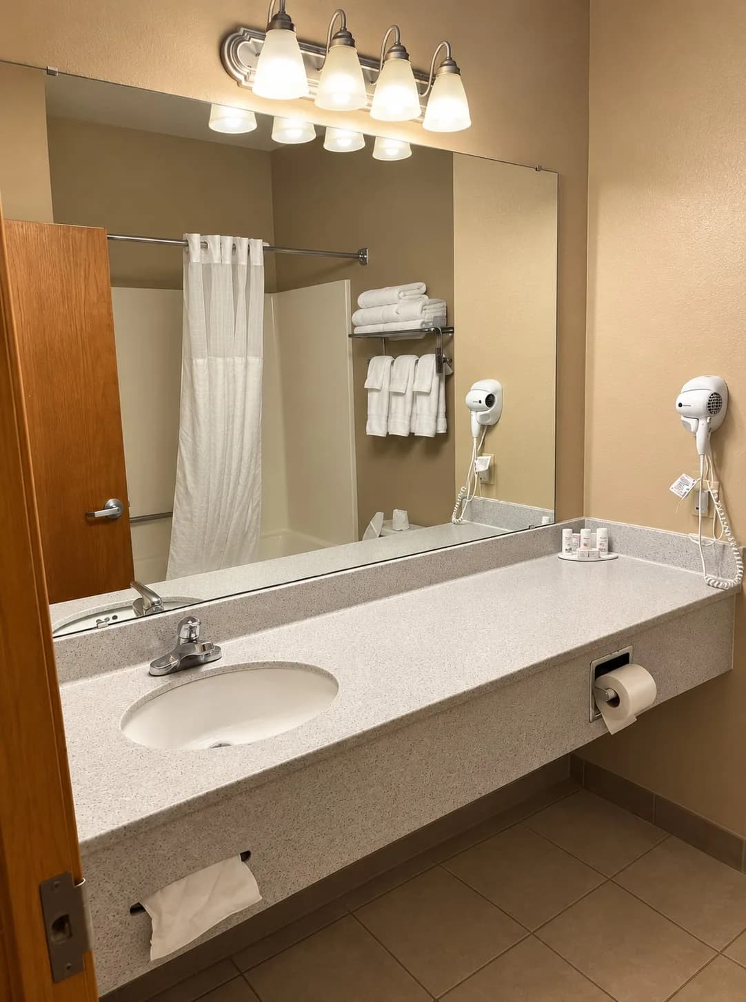 Bathroom vanity with a large mirror, hair dryer and towels