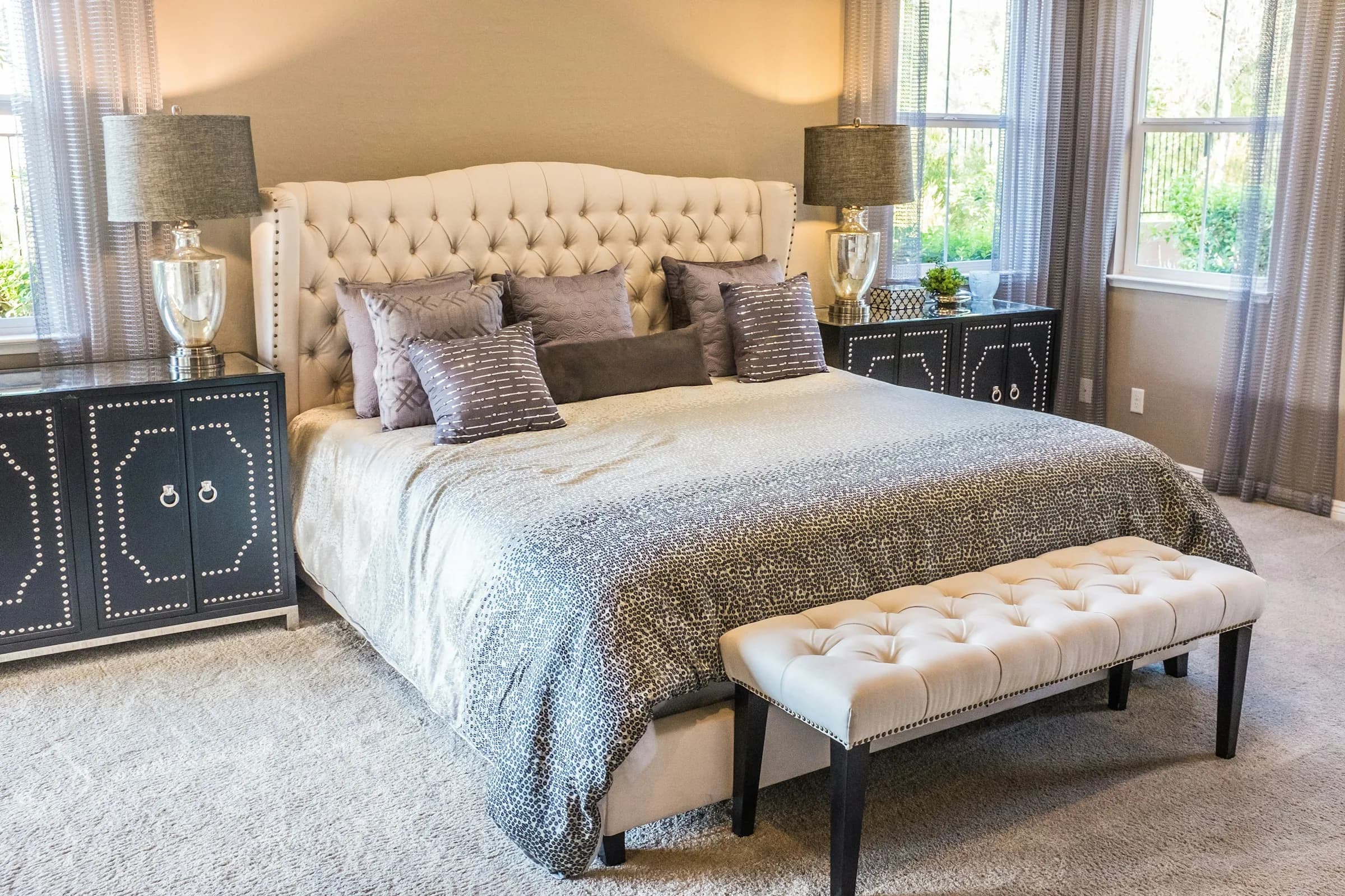 Deluxe King Studio Suite — Spacious bedroom with an upholstered headboard and bench