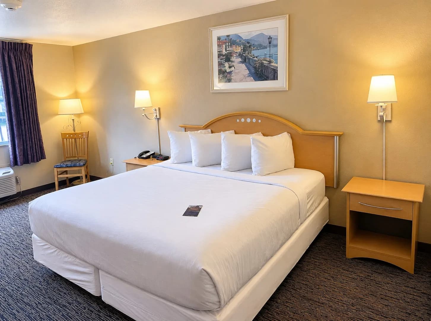 King Room — King room with a white king bed, bedside lamps and a reading chair