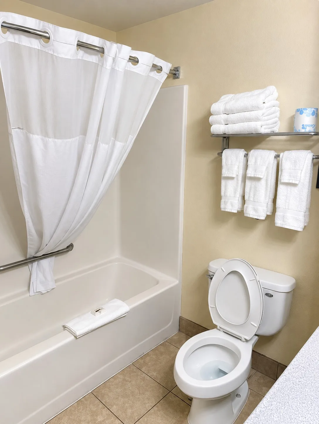 Guest bathroom with a tub, shower curtain and fresh towels