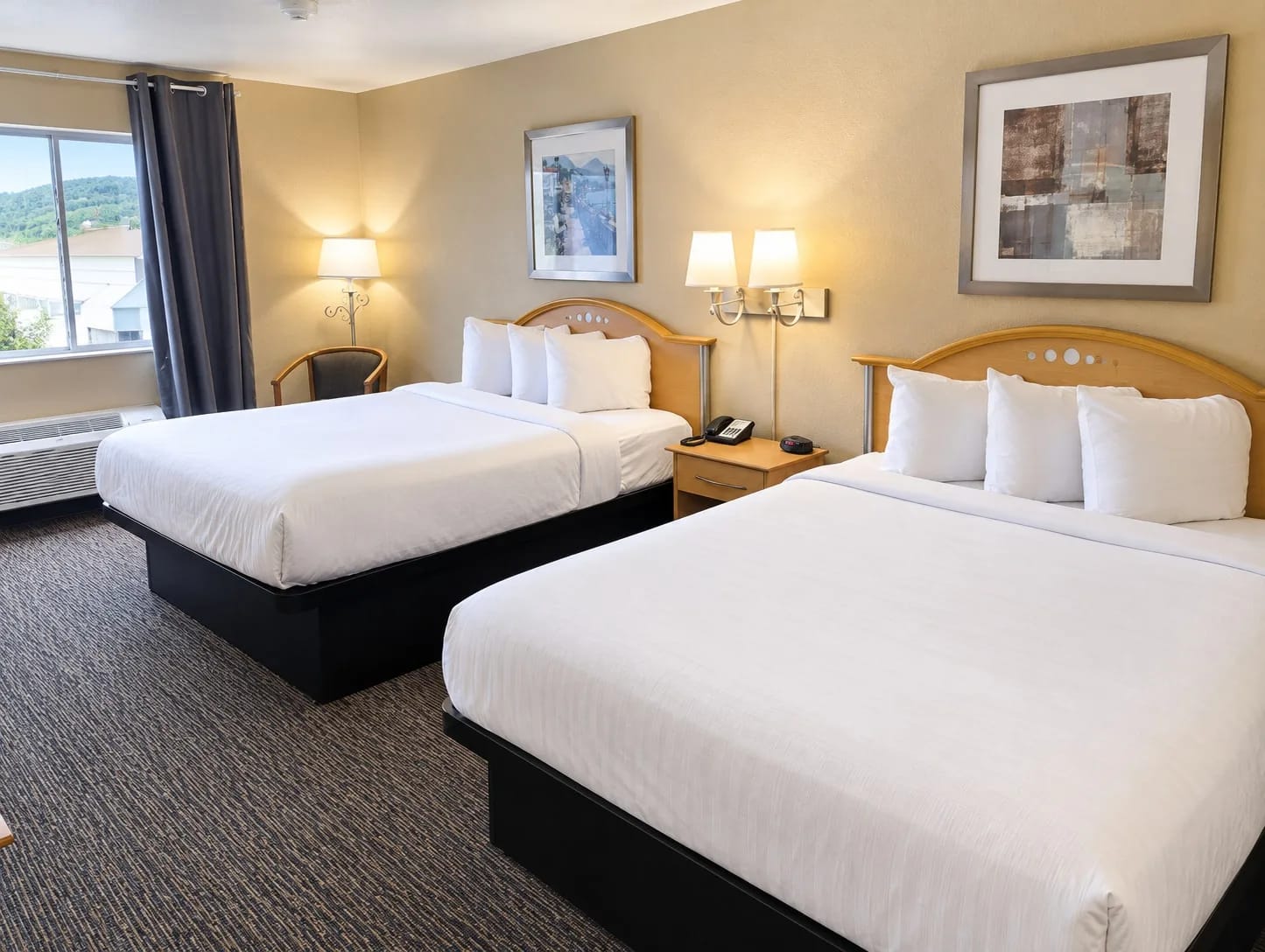Room with two queen beds, white linens and a window