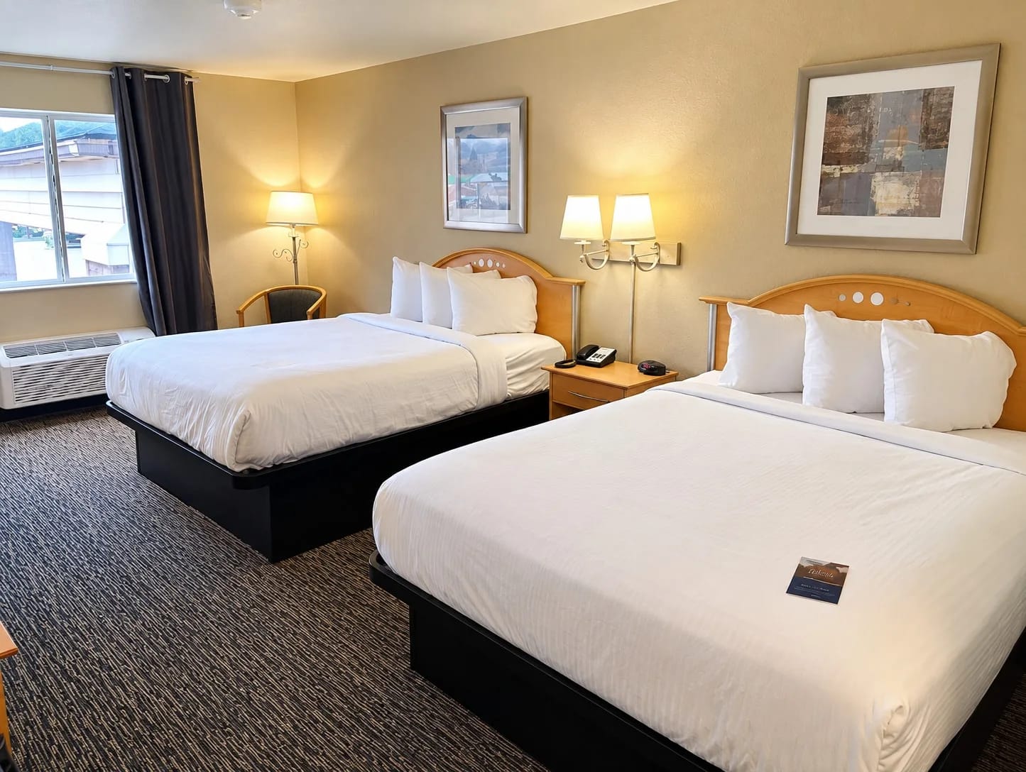 Two-bed room with bedside lamps, a phone and framed art